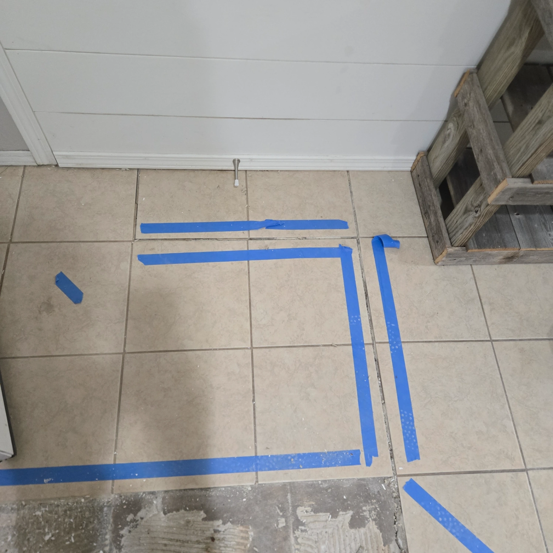 Floor tile area marked with blue tape for precise repair work in Orlando