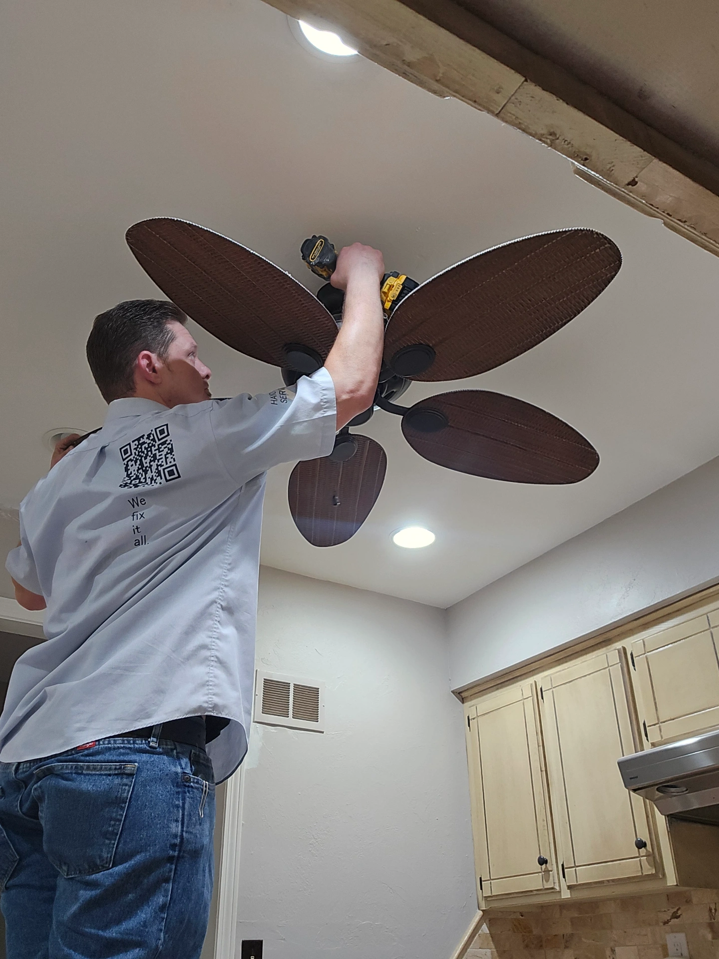 Stillwater Handymen LLC technician installing ceiling fan with drill