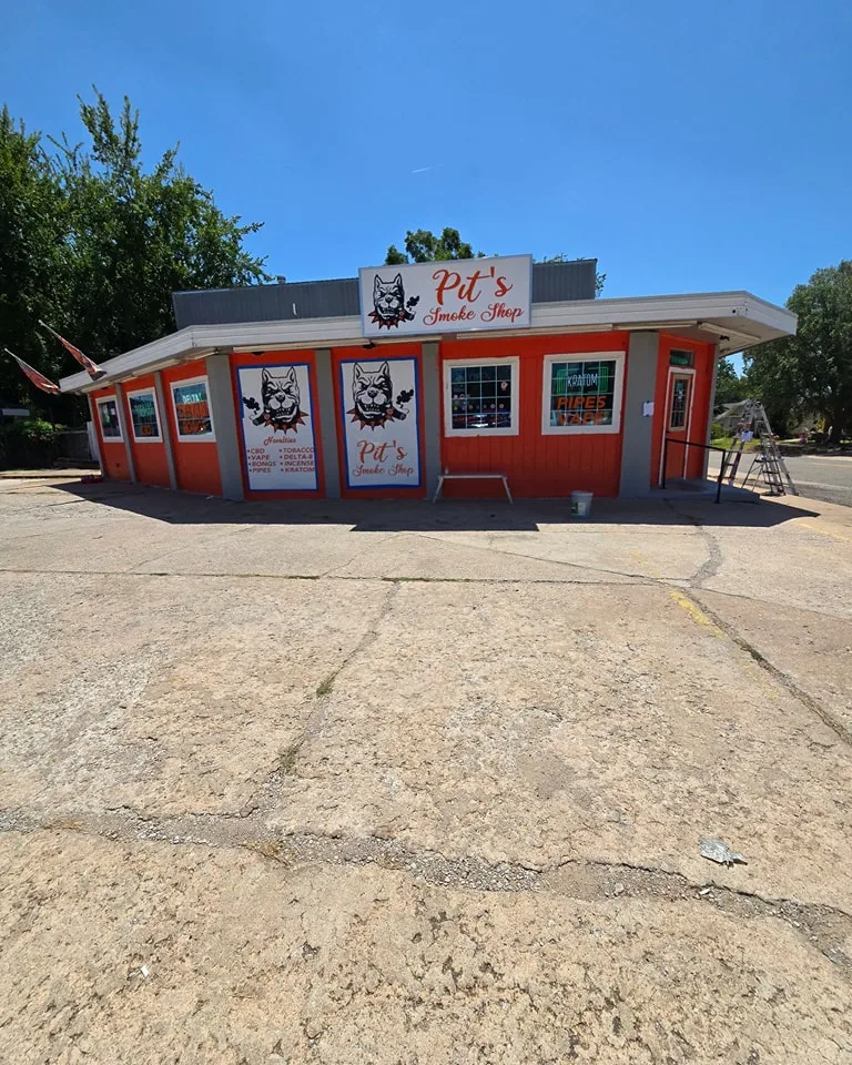 Pit's Smoke Shop exterior painting work in progress showing orange paint application