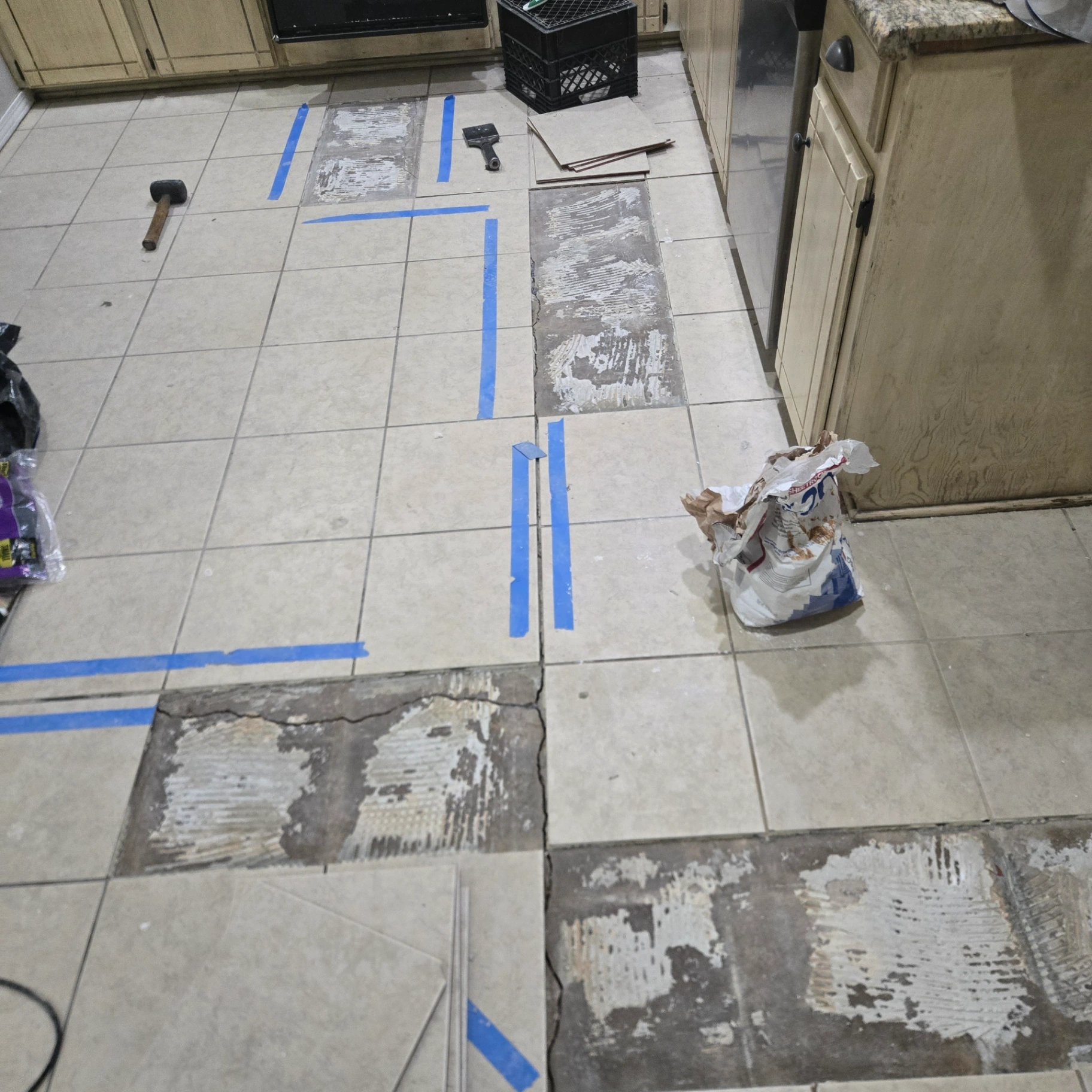 Kitchen floor tile replacement in progress showing removed damaged tiles in Stillwater, OK